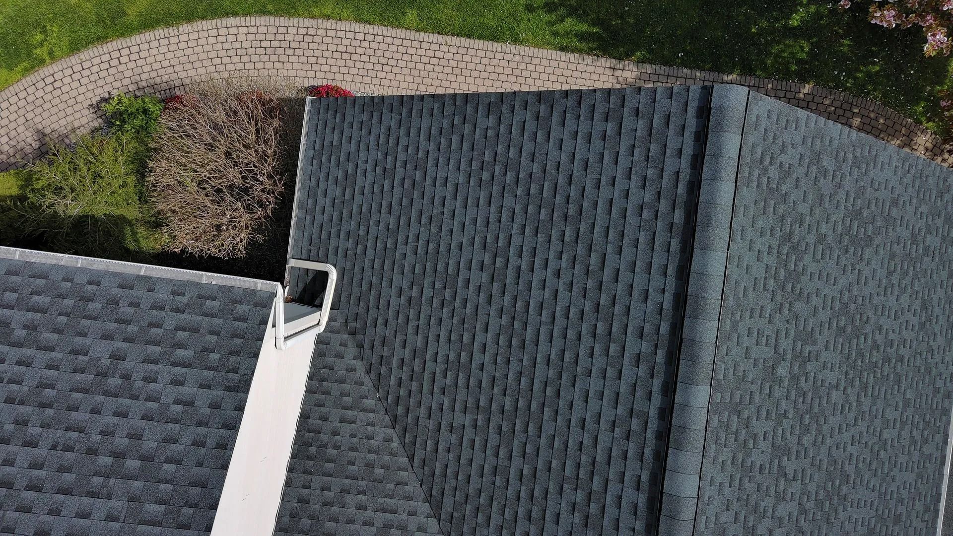 Overhead view of an asphalt shingle roof with a metal vent.