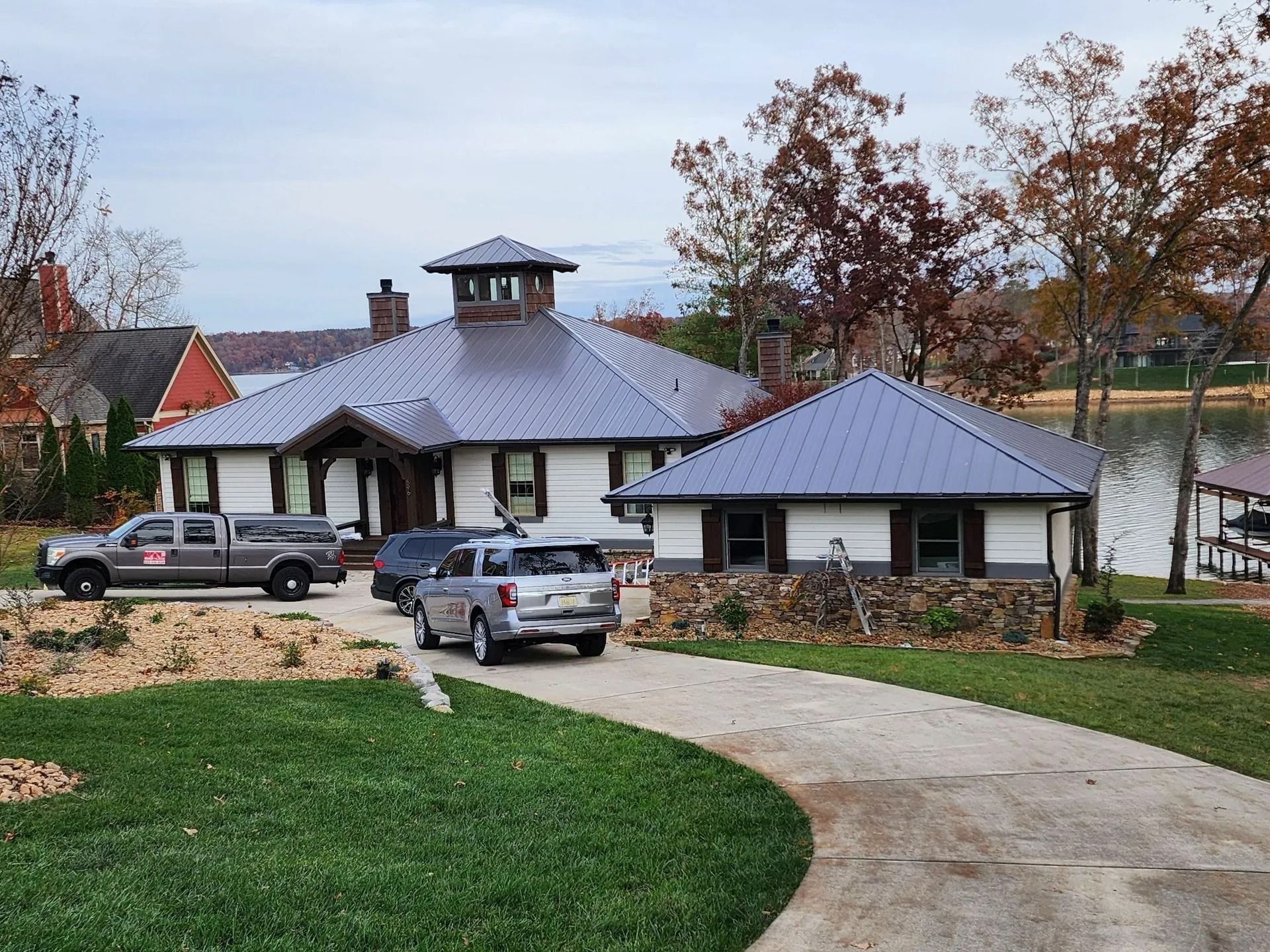 Waterfront home with a metal roof and paved driveway.